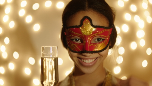 Shot of Black Woman Wearing Carnival Mask with Champagne Glass in Her Hand