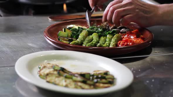 Placing mushrooms over the clay plate while preparing the salad, with zucchini waiting to be placed.