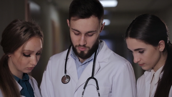 Doctor with Two Girls Interns Parses the Diagnosis of the Patient.