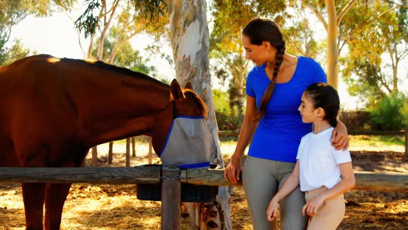 Mother and daughter stroking horse in ranch 4k