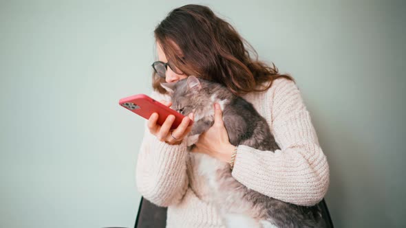 A Young Cheerful Woman Wearing Glasses Taking a Selfie with Her Cat