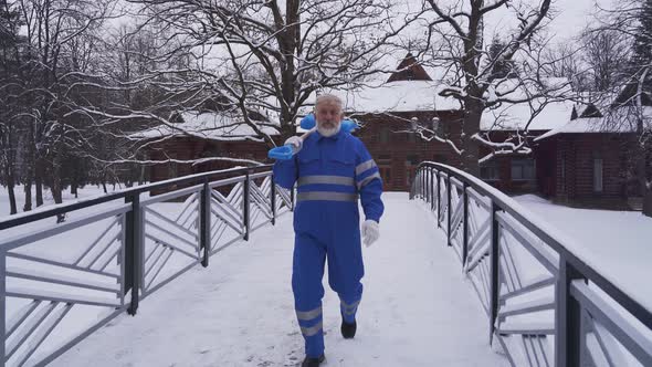 Old Cleaner Walking with Shovel on Shoulder.