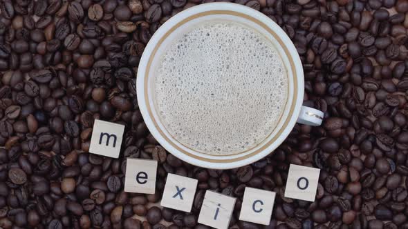 Top View of a Cup of Coffee on a Background of Coffee Beans with the Inscription Mexico
