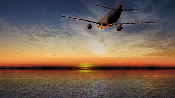 Airplane Flying Above Tropical Sea At Sunset