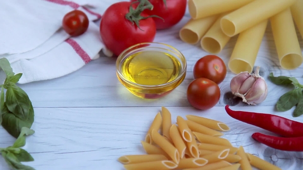 Olive Oil, Tomatos, Basil and Diffrent Kinds of Pasta on White Wooden Table