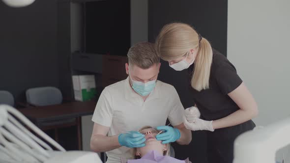 Two dentists, a man and a woman in protective masks and medical glove