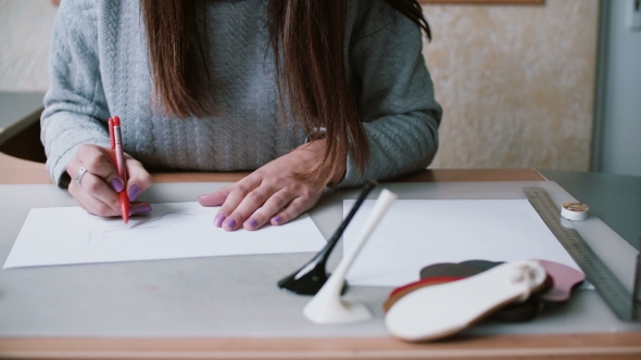 Woman Holding Pencil, Sitting at the Table and Drawing Sketch on Paper