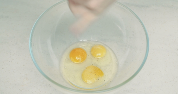 Beaten Eggs Being Sesoned with Pepper and Salt