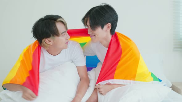 Portrait of Asian handsome man gay family holding LGBT flag and smile.