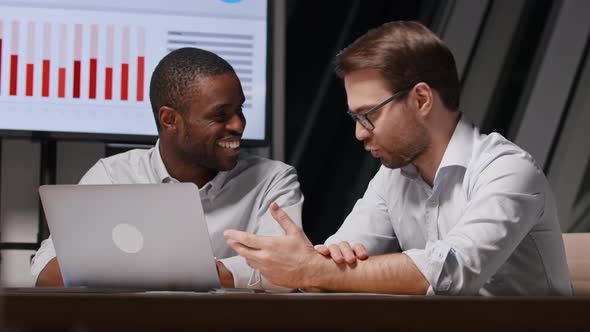 Smiling businessmen working with statistics using laptop and multimedia tv