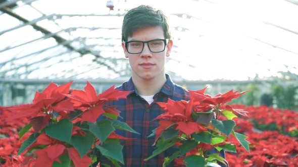 Happy Gardener Shows Red Flowers and Smiling To Camera