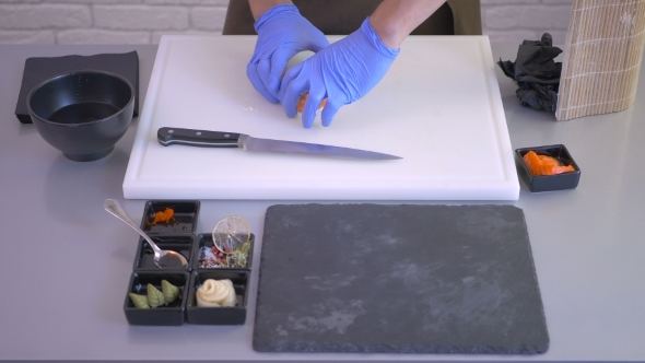 Cook Forming a Sushi Roll From a Small Pieces on a Board