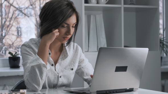 Tired Woman in a Works at a Laptop in the Office