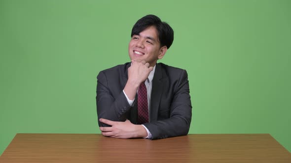 Young Handsome Asian Businessman Against Green Background