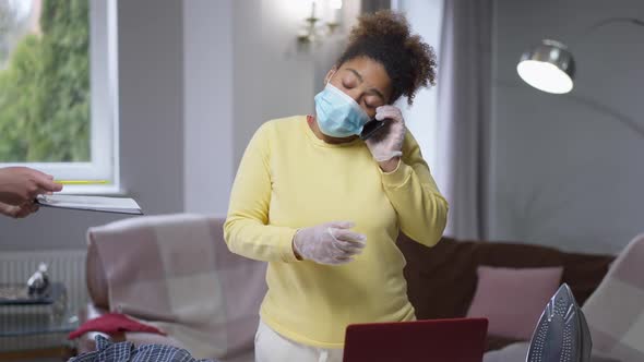 Busy African American Woman on Covid Face Mask Typing on Laptop Keyboard Answering Phone and Signing