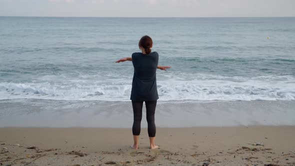 Mature Woman Doing Morning Exercises on the Beach Back View