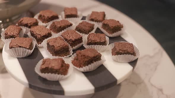 Young woman take of round plate with baked brownies, delicious chocolates biscuits, close up shot.