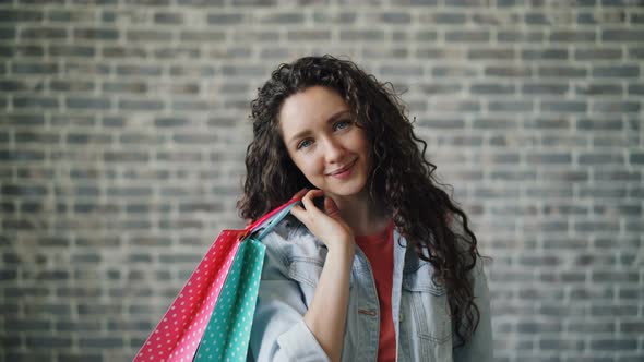 Portrait of Attractive Shopaholic Holding Paper Shopping Bags Looking at Camera