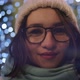 A beautiful smiling brunette in glasses in a winter hat in the night city in the background - VideoHive Item for Sale