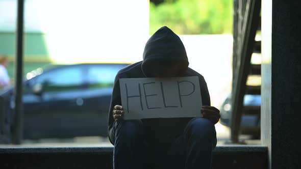 African-American Teenager Holding Help Cardboard Sign, Asking for Alms in Street