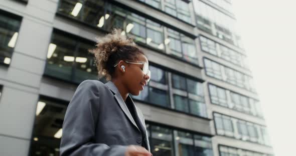 A Woman Wearing Headphones Listens to Music and Dances Outside Office Building