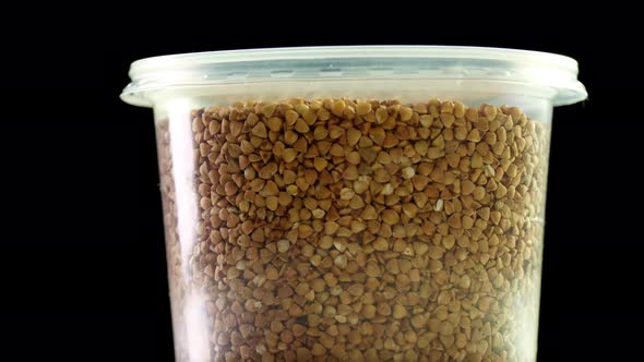 Close-up, Buckwheat Into Plastic Packaging, Box, Rotates on Black Background. Grocery Online