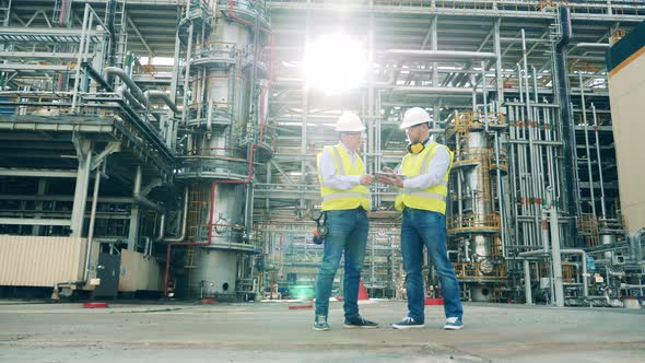 Oil Refinery Engineers in Safety Wear are Discussing a Project