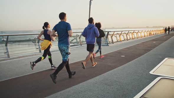 Group of Millennial Runners Practicing Morning Jog Workout on Sports Path Slow Motion