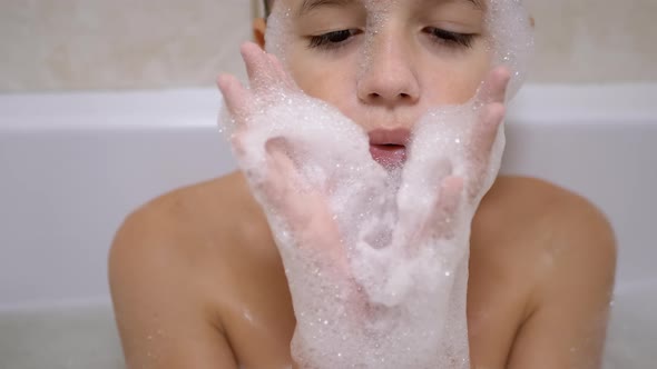 Boy Bathes in Bathroom Plays with Bubbles of Soapy Foam Makes Funny Foam Masks