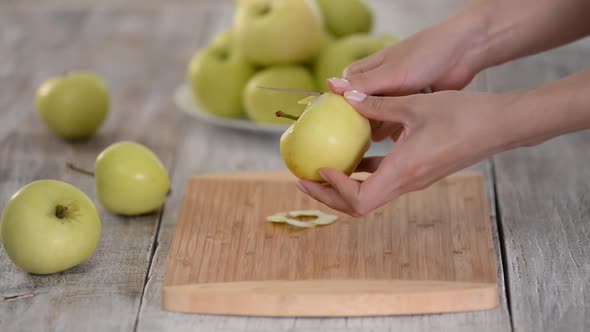 Hands of the Cook Peel a Green Apple with a Knife