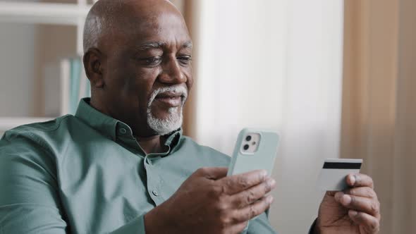 Smiling Elderly Mature Man Hold Telephone and Credit Card Male Customer Make Online Purchase Pay