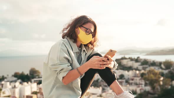 A Young Woman in Protective Mask Unlocks Her Smartphone with a Face Id