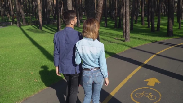 A Cute Couple Is Walking Along the Path in the Forest.