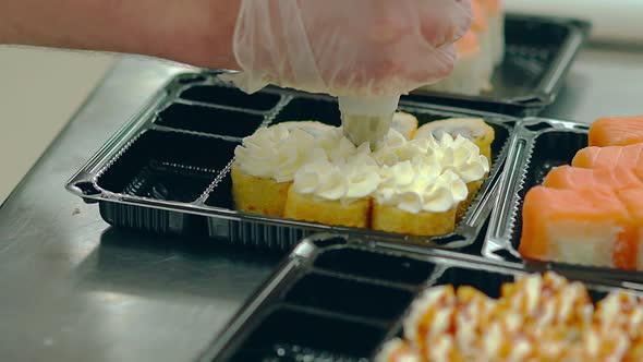 Cook Adds a White Cream To Japanese Rolls with a Fried Omelette.