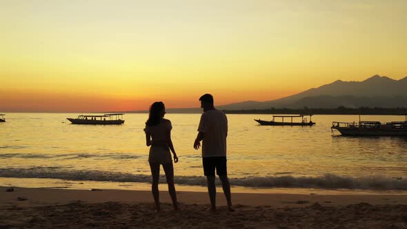 Teenage lovers sunbathing on idyllic lagoon beach time by shallow ocean with white sand background o