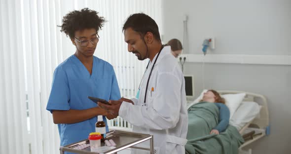 Multiethnic Medical Team with Digital Tablet Examining Female Patient in Hospital Ward