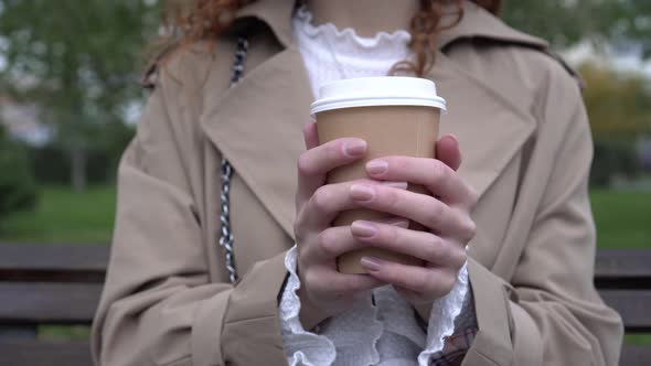 A Woman Holds a Paper Cup with Takeaway Coffee