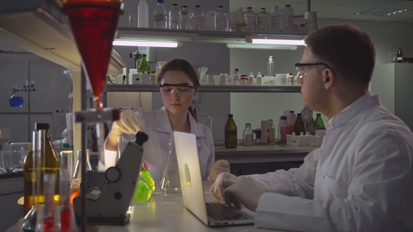 Scientist with Assistant Working in Laboratory in the Evening.