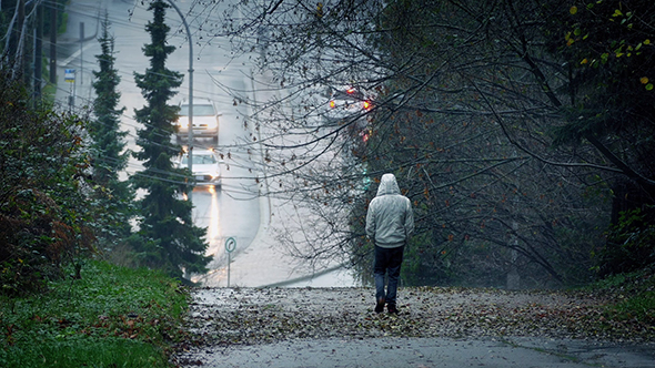 Man Walking Down Hill On Rainy Day
