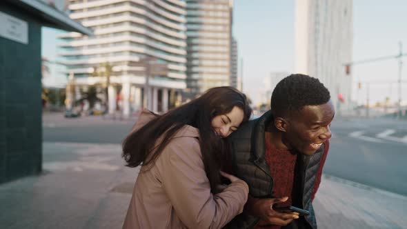 Cheerful Multiethnic Couple Laughing at Joke in City