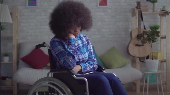 Sad and Lonely Disabled African American Woman with an Afro Hairstyle in a Wheelchair Sitting Alone