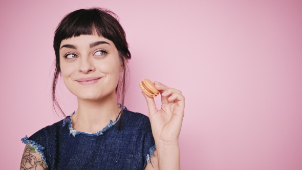 Attractive Brunette Eats Macarons Isolated on Bright Backgrounds