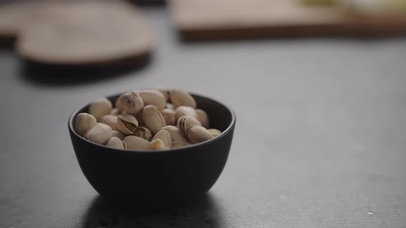 Slow Motion Man Hand Take Pistachio From Black Bowl on Terrazzo Surface