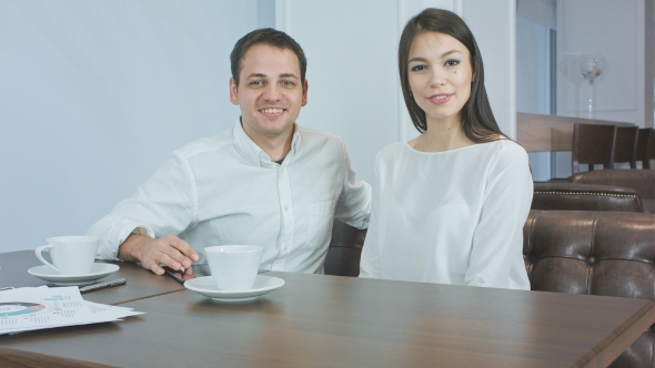 Cheerful Business Couple Talking To the Camera Sitting in a Cafe