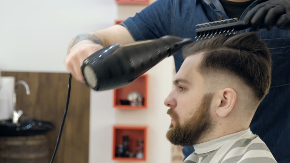 Barber Getting Groomed at Hairdresser with Hair Dryer While Sitting in Chair at Barbershop