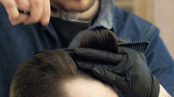 Master Cuts Hair and Beard in the Barber Shop. Black Gloves with Tattoos Off of Hands.