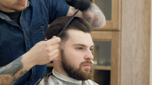 Portrait of Attractive Young Man Getting Trendy Haircut. Male Hairdresser Serving Client