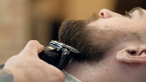 Horizontal Portrait of a Barber Shaping Beard of His Client Using a Trimmer