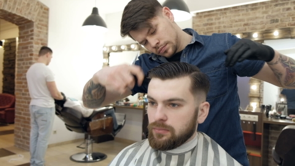 Barber Style. Male Barber in Plaid Shirt Combing Hair of a Male Client at Barbershop