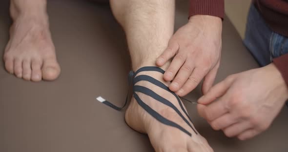 Physiotherapist Sticks Kinesio Tapes to the Foot of Patient Kinesiology Taping Kinesiological